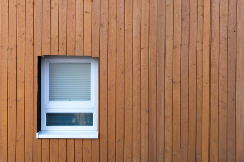 Helle Holzfassade mit neuem weißen kleinen Fenster